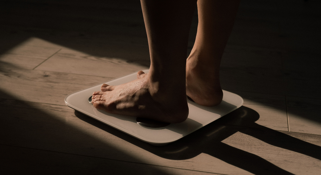 A person standing on a weight where only the lower parts of the legs are visible as well as dramatic shadows.
